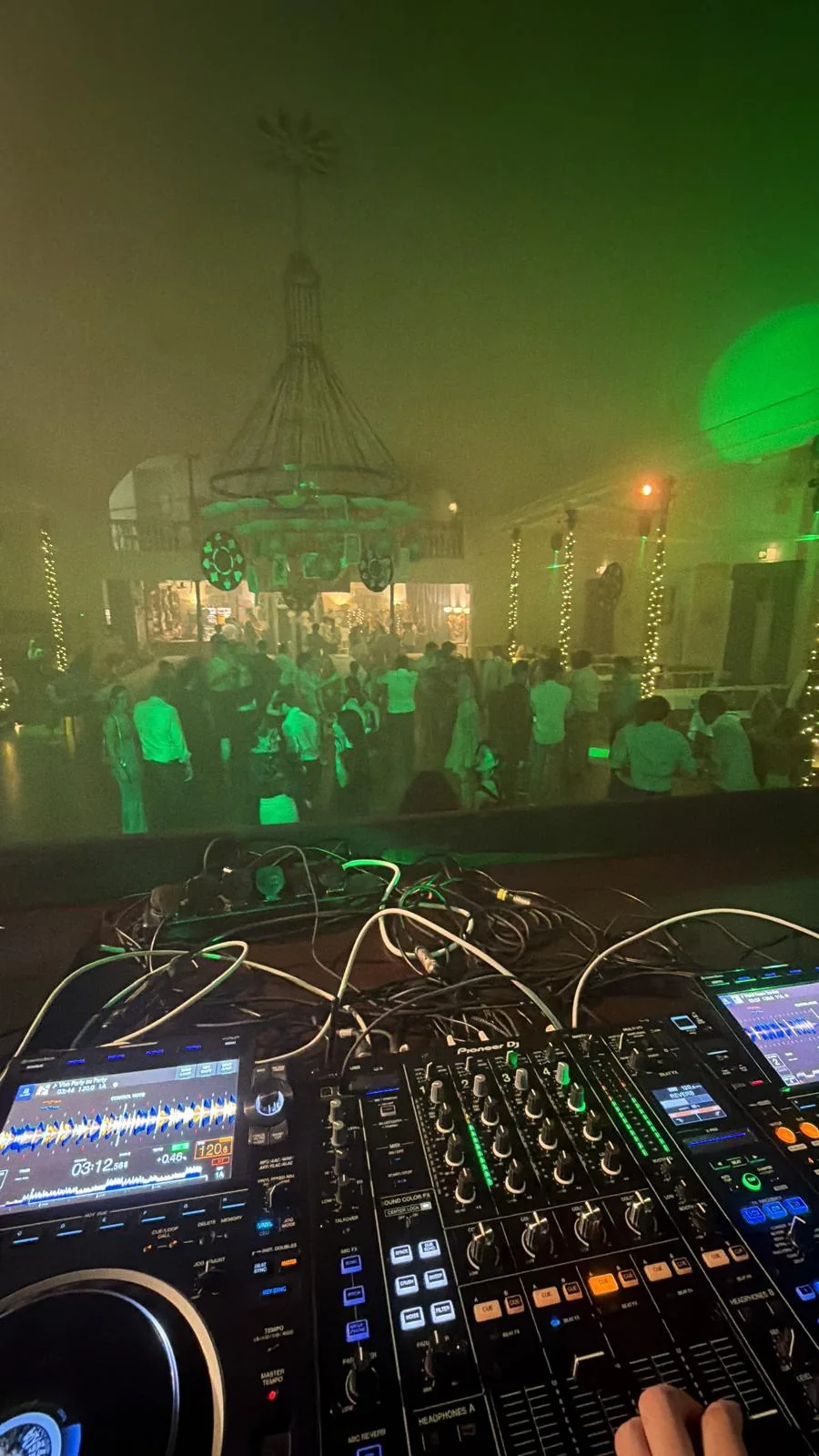 DJ-Technik mit Blick in einen beleuchteten Festsaal
