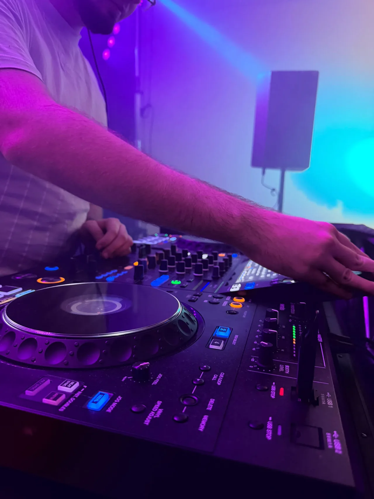 DJ am Pioneer-Controller im blau-violetten Bühnenlicht