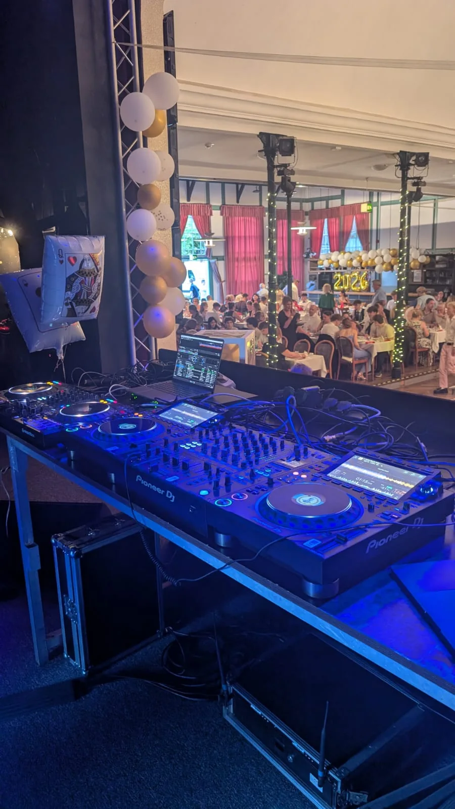 Pioneer-DJ-Technik mit Blick auf einen geschmückten Festsaal mit Gästen