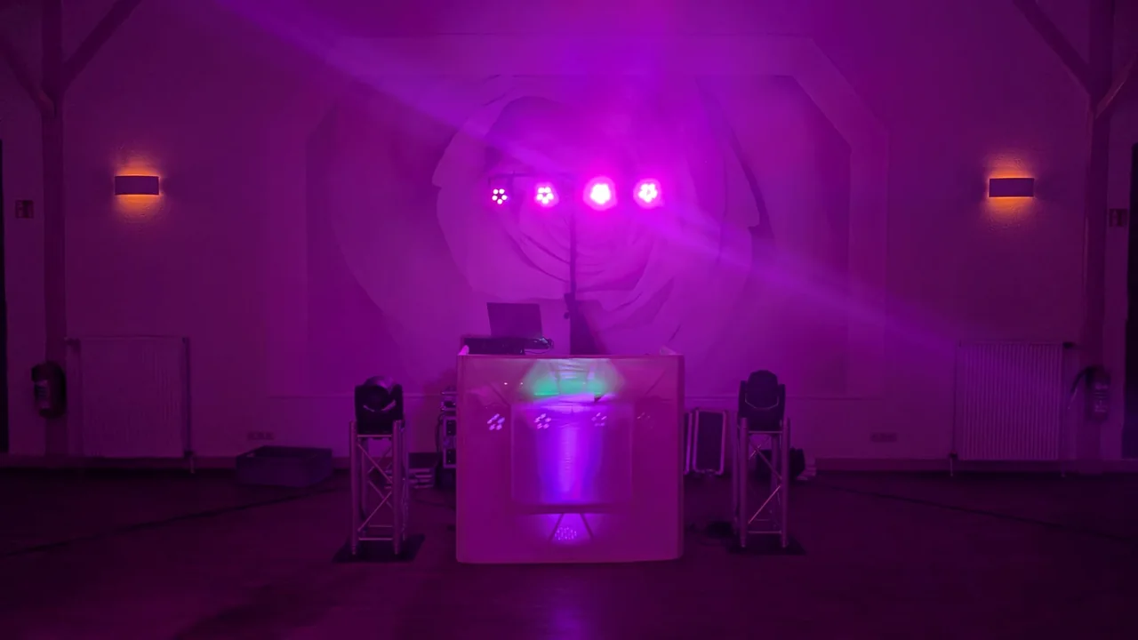 Weißes DJ-Pult mit magentafarbener Lichtinszenierung und Moving Heads