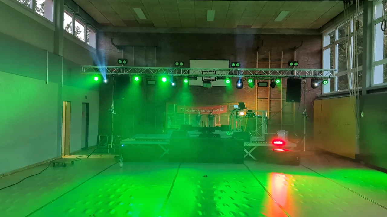 Traversen, Bühne und grüne Lichttechnik in einer Veranstaltungshalle